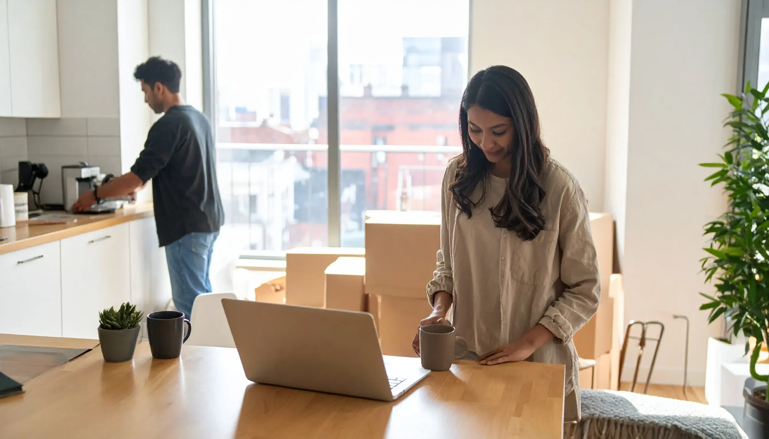 Simplify your move and set up utilities easily – Delisa Miller Manchester Couple unpacking boxes in a bright Manchester apartment while setting up home utilities online, representing Delisa Miller’s hassle-free moving support.